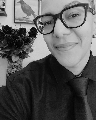 King Gaia shadow work coach and Reiki alchemist smiling in black and white portrait with tarot cards in the background, offering sacred guidance for self-discovery and healing.