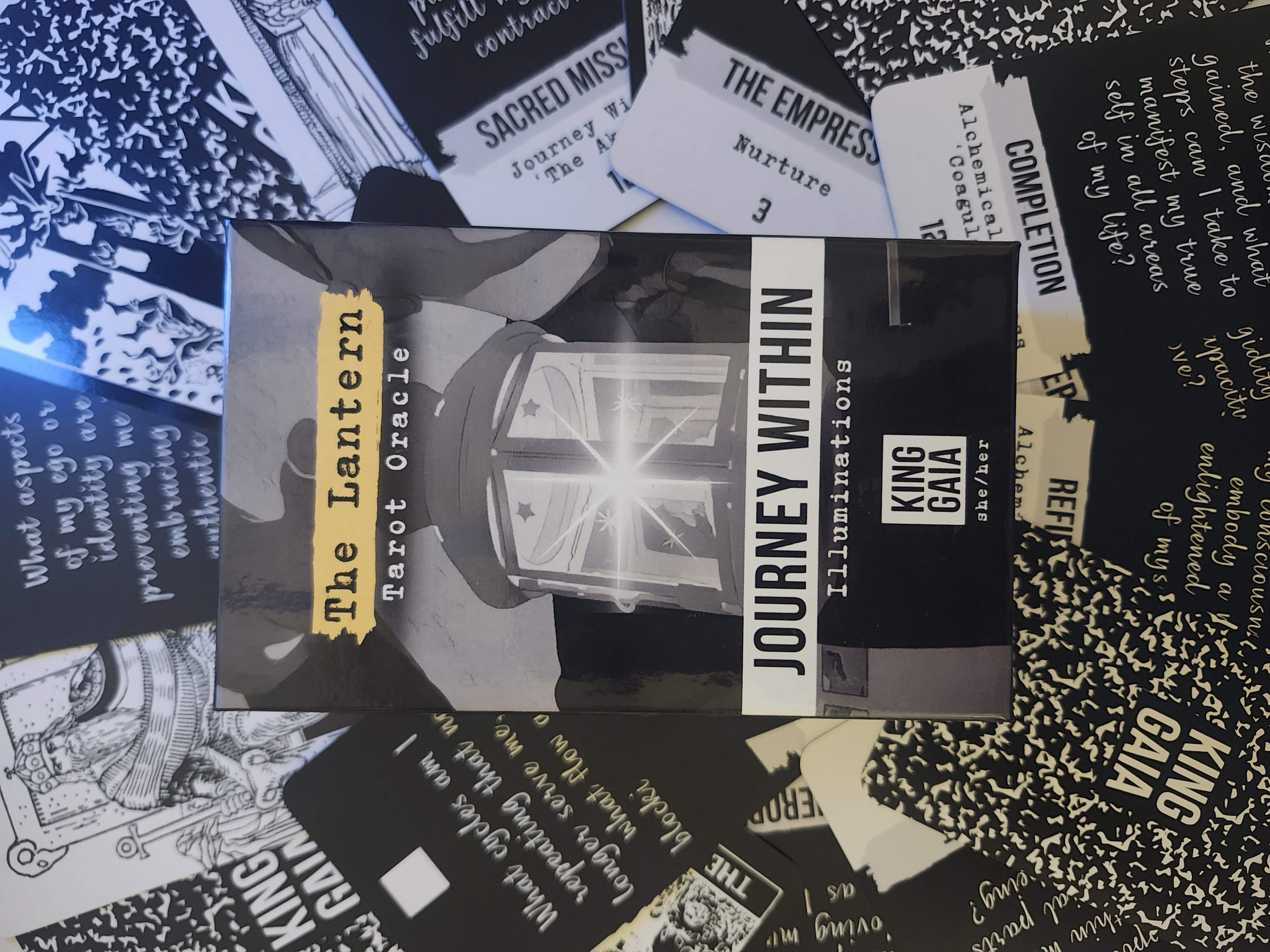 The Lantern Tarot Oracle – Journey Within Illuminations deck by King Gaia displayed with black-and-white cards. A sacred tool for shadow work, self-love, and inner illumination.