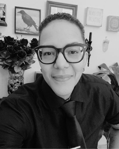 King Gaia shadow work coach and Reiki alchemist smiling in black and white portrait with tarot cards in the background, offering sacred guidance for self-discovery and healing.